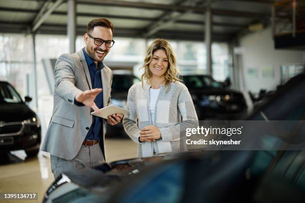 happy salesman selling the car to his female customer in a showroom. - salesman bildbanksfoton och bilder