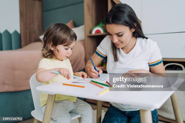 mother and her little girl drawing together at home. - livro de colorir imagens e fotografias de stock