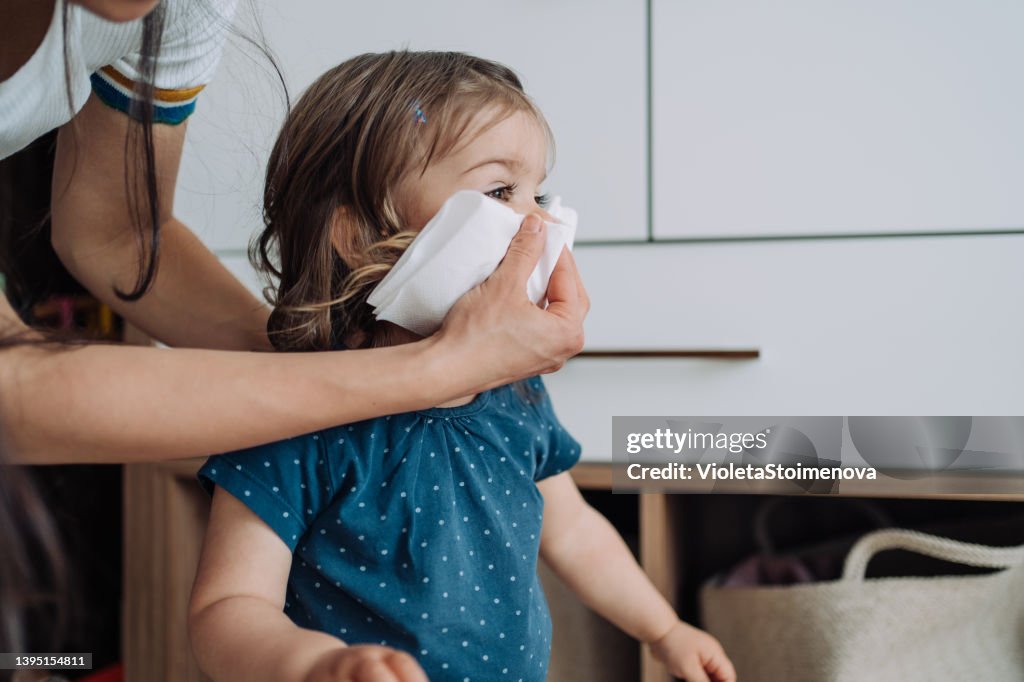 Mother helping daughter to blow her nose.