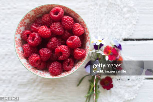 bowl with raspberries and wild flowers on side, high angle view - hallon bildbanksfoton och bilder