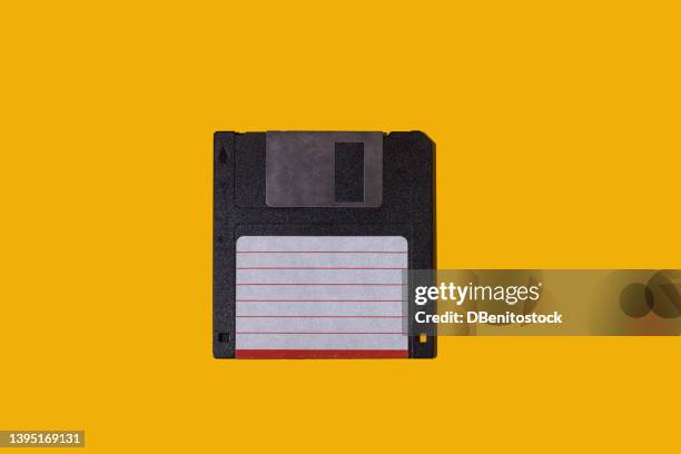 black retro 3.5" floppy diskette with white and red label on yellow background. concept of computing, computer, storage, vintage, disk and data storage. - obsolete software stock pictures, royalty-free photos & images