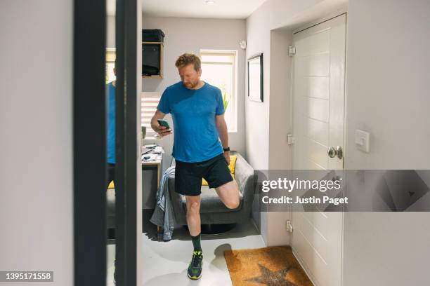 mature man stretches and checks his smartphone before going out for a run - men jogging stock pictures, royalty-free photos & images