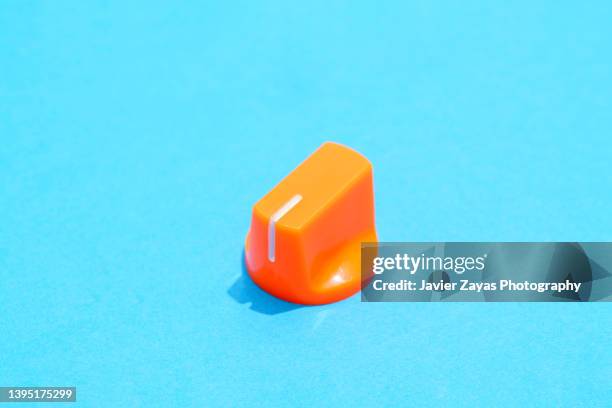 orange plastic knob on blue background - electrical switch stock-fotos und bilder