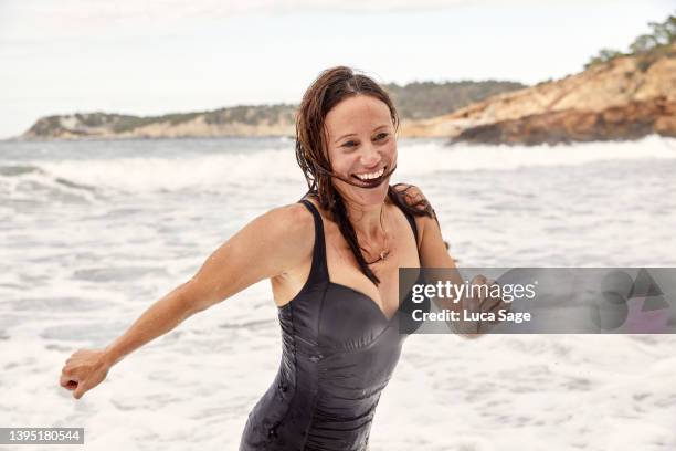 fun sea swim in wild waves on the beach - badeanzug stock-fotos und bilder