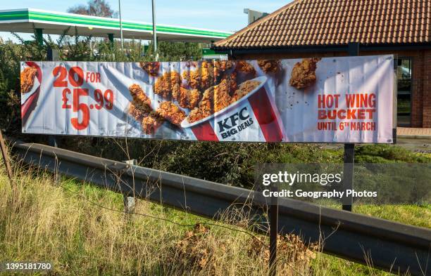 Banner sign advertising KFC Hot Bucket Wings, Kentucky Fried Chicken outlet, Martlesham, Suffolk, England, UK.