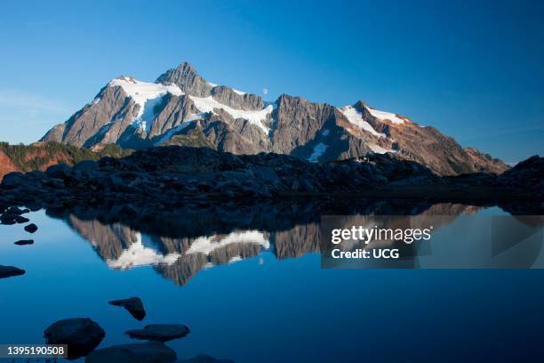 The moon rises over glaciated Mount Shuksan, an iconic peak of the North Cascades range of northern Washington.