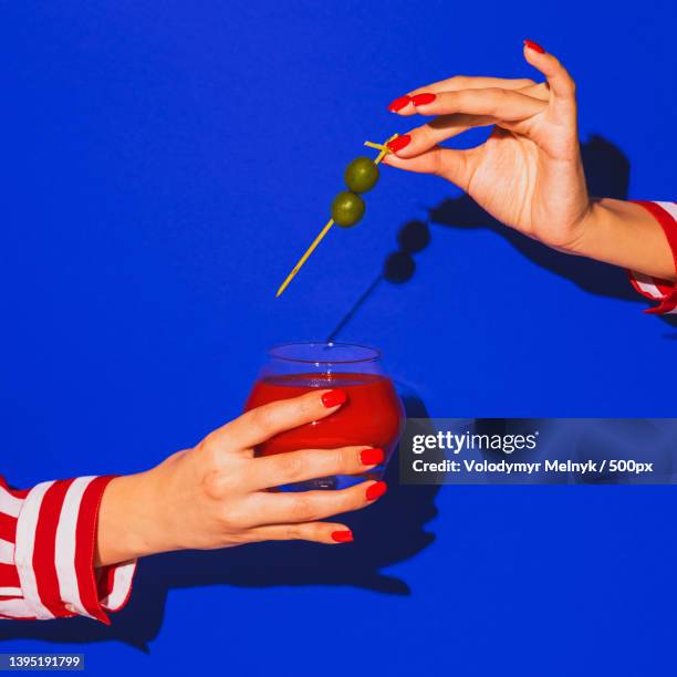 female hand holding glass with cocktail isolated on bright blue neon - barman tequila stockfoto's en -beelden