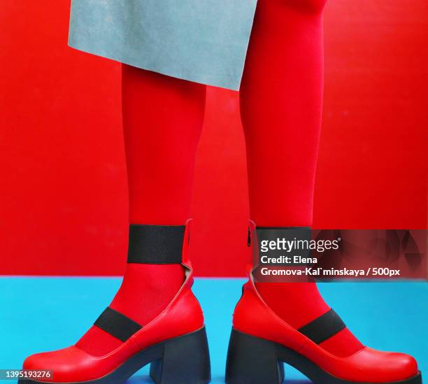 low section of woman wearing red socks while standing on red and blue background - zapatos rojos fotografías e imágenes de stock