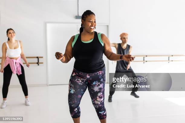 african woman instructor showing dance moves to students in dance class - body types stock-fotos und bilder