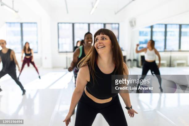 mature woman performing fitness dance in gym class - large group of people photos et images de collection