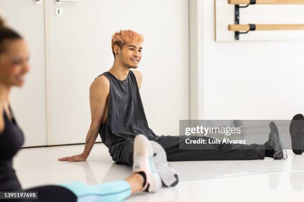 young asian man sitting on the floor doing stretching exercises in the dance studio - body conscious stock pictures, royalty-free photos & images