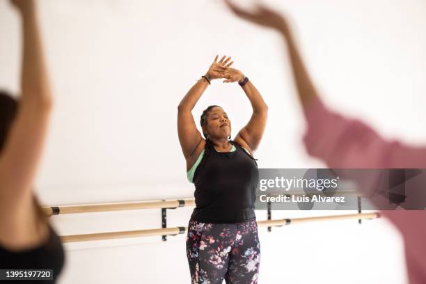 plus size african woman doing stretching workout in a fitness class - woman dance studio stock pictures, royalty-free photos & images