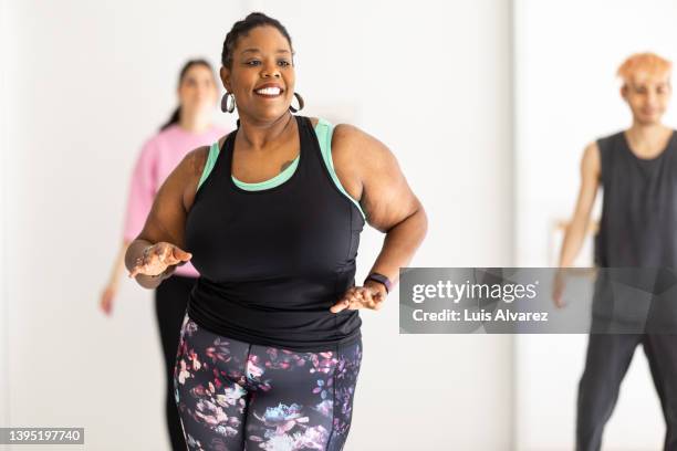 smiling african woman enjoying dancing at fitness studio - zumba stockfoto's en -beelden