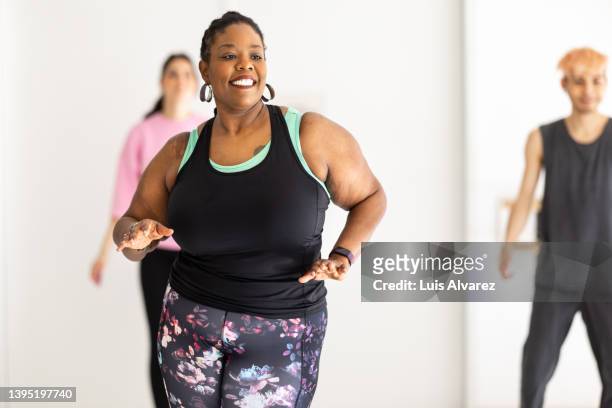 smiling african woman enjoying dancing at fitness studio - fat people stock pictures, royalty-free photos & images