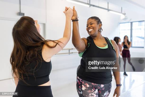cheerful women giving each other high five at dance class - body positive stockfoto's en -beelden