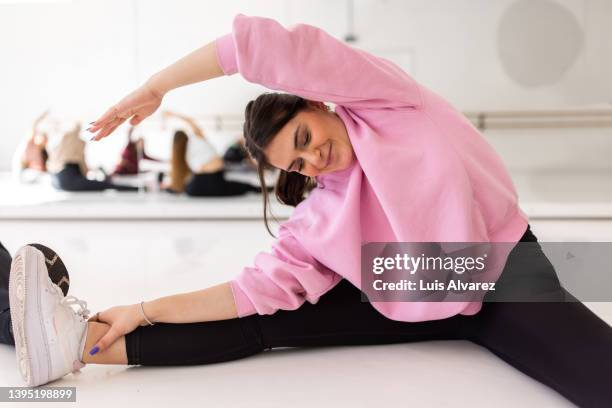 young woman doing side stretching workout at dance class - warm up exercise indoor stock pictures, royalty-free photos & images