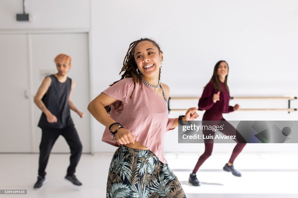 Smiling young woman doing dance in fitness studio