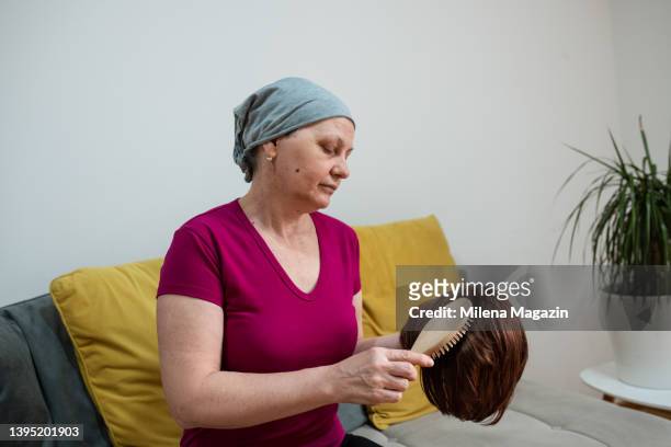 portrait of a cancer survivor, brushing her wig - toupee stockfoto's en -beelden