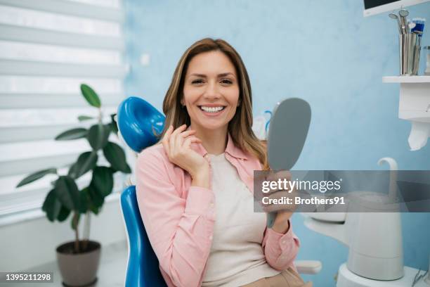 a happy woman looking herself in the hand held mirror - patients brothers 個照片及圖片檔