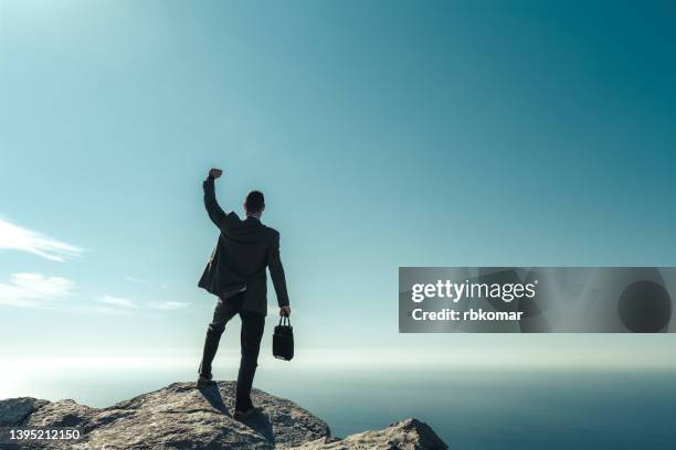 silhouette businessman holding a suitcase on mountain peak. achievement leadership business concept of victory and success - leadership fist ストックフォトと画像