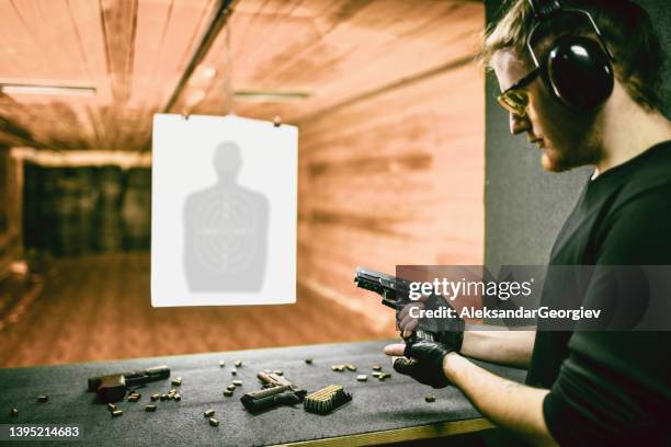 tirador masculino probando la mejor arma de fuego para el trabajo en el rango - agujero de bala fotografías e imágenes de stock