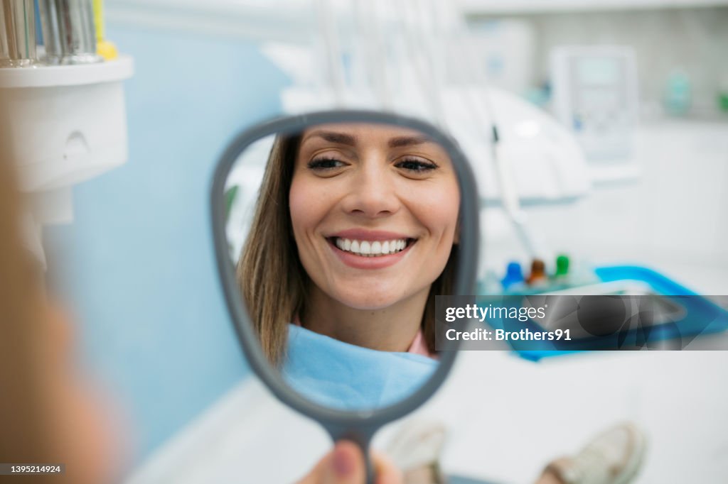 A happy woman looking herself in the hand held mirror