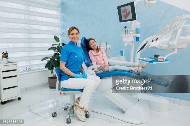 a professional female dentist sitting next to a little girl in her office - patients brothers 個照片及圖片檔
