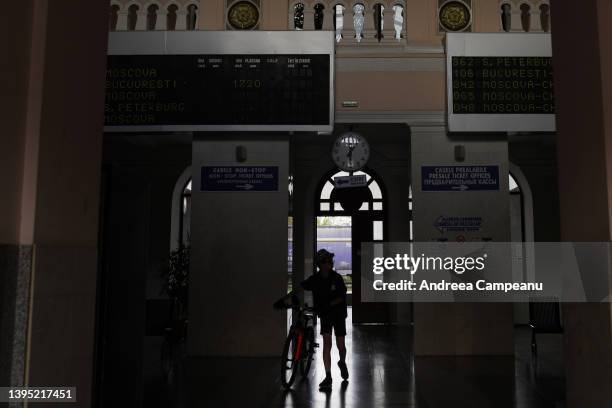 Child carries his bike out the train station, as builboards still show the Moskow-Chisinau train, that was canceled when the pandemic started, on May...
