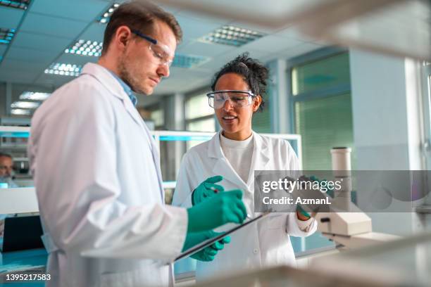 mixed mid adult science team in lab wear - epidemiology research stock pictures, royalty-free photos & images