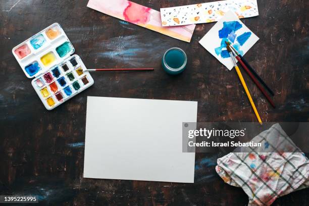 top view of watercolor paint palettes, papers and paintbrushes on a table. - malen papier pinsel stock-fotos und bilder