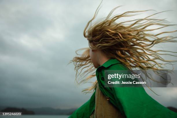 a girl dancing with wild hair in moody light - blazen stockfoto's en -beelden