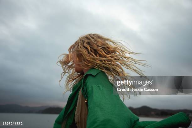 a girl dancing with wild hair in moody light - blond haar stock-fotos und bilder