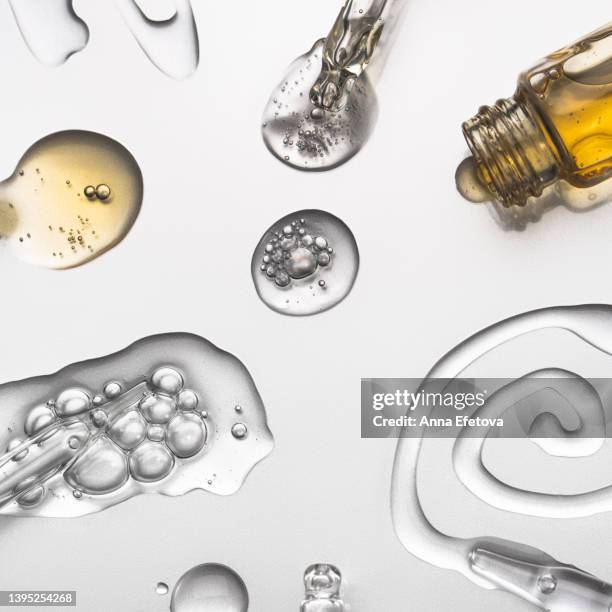 many glass pipettes spilling drops of different moisturizing lotions on luxury silver background. polyglutamic acid is new hyaluronic acid. macro photography - jojoba stockfoto's en -beelden