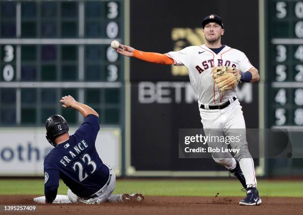 Alex Bregman of the Houston Astros turns a double play in the fourth inning as Ty France of the Seattle Mariners slides into second base at Minute...