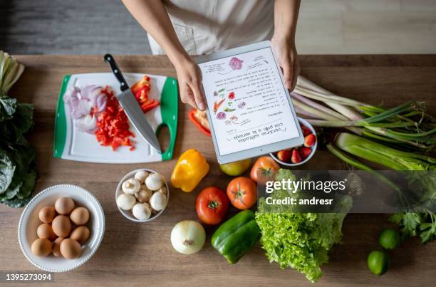 plan rapproché sur une femme cuisinant à la maison suivant une recette en ligne - suit photos et images de collection