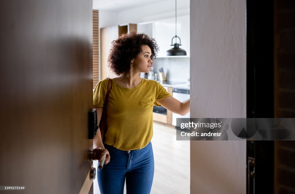 Mujer en la puerta saliendo de su casa y activando la alarma