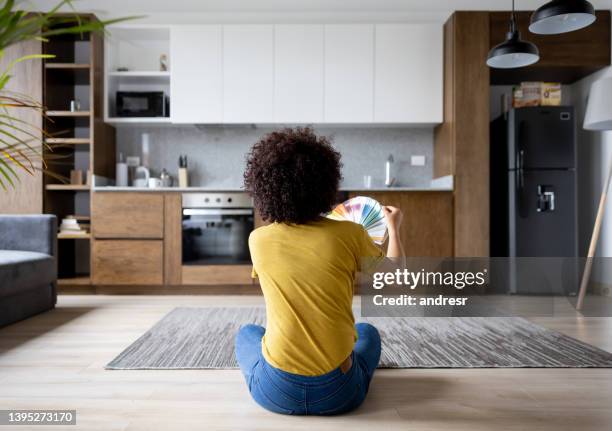 woman at home choosing a color to paint the walls - decorating loft imagens e fotografias de stock