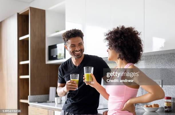 fit couple drinking a green detox juice at home - smoothie stockfoto's en -beelden