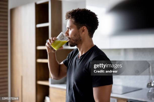 fit man drinking a green juice for breakfast at home - shaking drink stock pictures, royalty-free photos & images