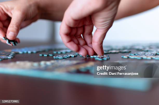 close-up of women's hands playing with a jigsaw puzzle - part of the solution stock pictures, royalty-free photos & images