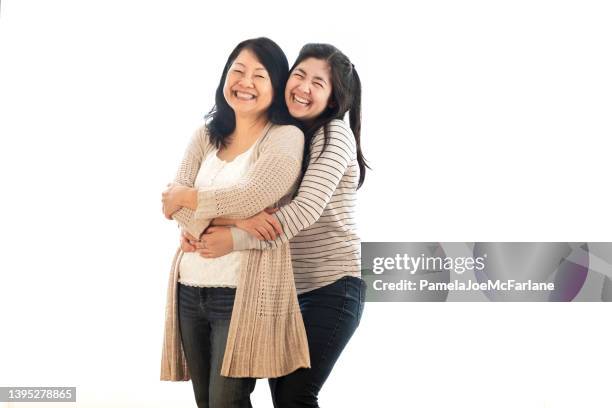 smiling eurasian adult daughter hugging mature asian mother, white background - family white background stock pictures, royalty-free photos & images