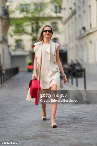 Alba Garavito Torre wears black sunglasses from Ray Ban, a beige short dress with silver nailed / studded collar from Barbara Bui, a beige sleeveless...