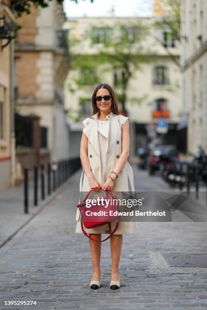 Alba Garavito Torre wears black sunglasses from Ray Ban, a beige short dress with silver nailed / studded collar from Barbara Bui, a beige sleeveless...