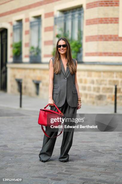 Alba Garavito Torre wears black sunglasses from Ray Ban, a dark gray sleeveless / oversized blazer jacket from Barbara Bui, matching dark gray large...