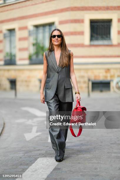 Alba Garavito Torre wears black sunglasses from Ray Ban, a dark gray sleeveless / oversized blazer jacket from Barbara Bui, matching dark gray large...