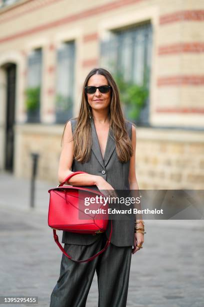 Alba Garavito Torre wears black sunglasses from Ray Ban, a dark gray sleeveless / oversized blazer jacket from Barbara Bui, matching dark gray large...