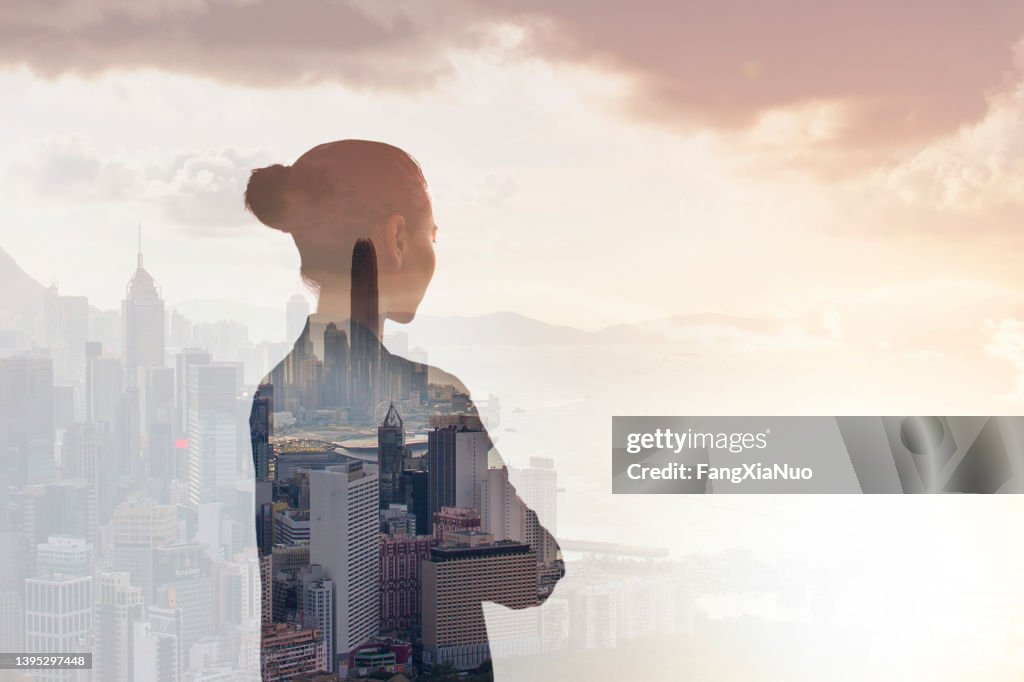 Young woman standing in contemplation in urban city reflection of Hong Kong, China