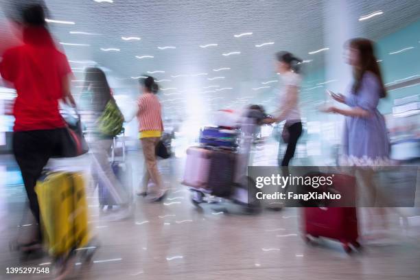unscharfe passagiere, die sich auf reisen mit gepäck durch das flughafenterminal bewegen - slow shutter speed crowd stock-fotos und bilder