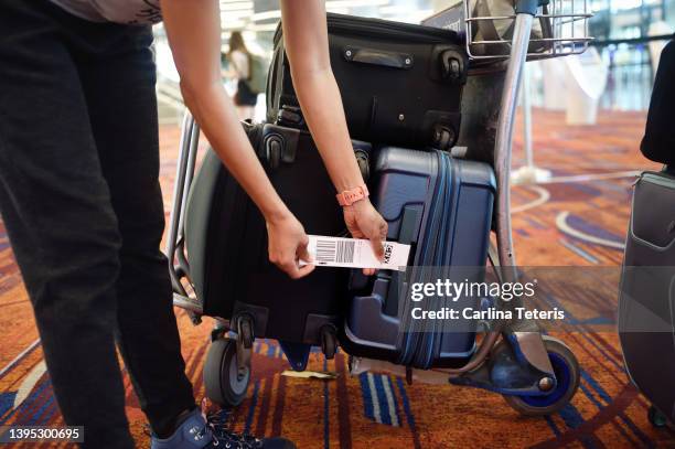 woman attaching a baggage tag to her suitcase - miteinander verbunden stock-fotos und bilder