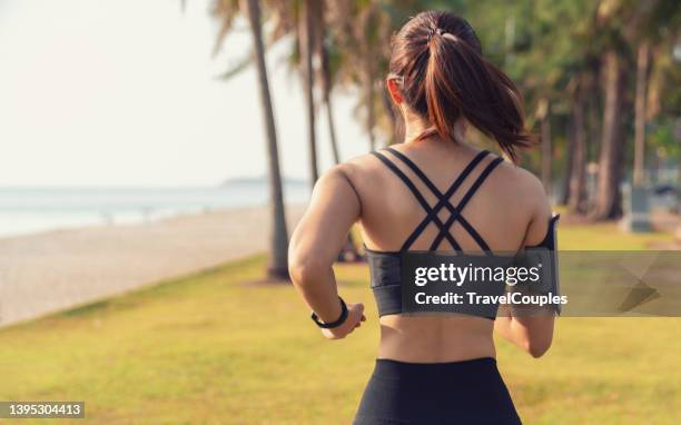 back view of young fitness sports women runner running in the park. healthy fitness woman jogging outdoors. sport and health concept - com as mãos nas cadeiras - fotografias e filmes do acervo